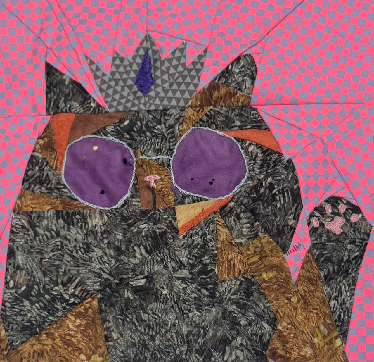 Pieced cat wearing a crown and purple sunglasses on a pink checkered background